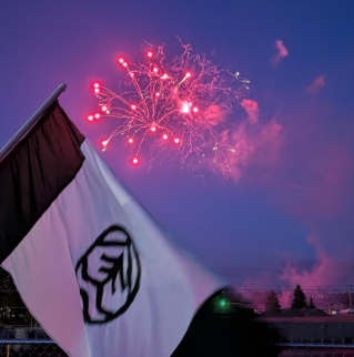 A Marysville flag flying in front of fireworks at Ebey Waterfront Park.