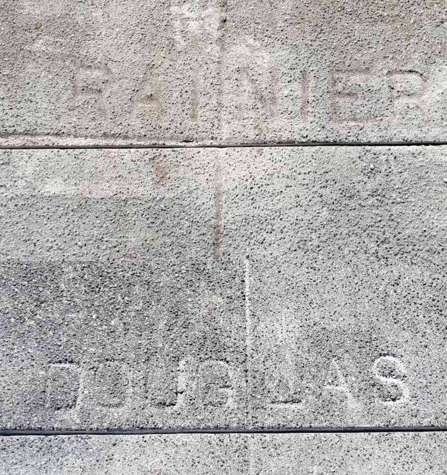 A photo of a sidewalk with street names inscribed into them: Rainer Street and Douglas Street.